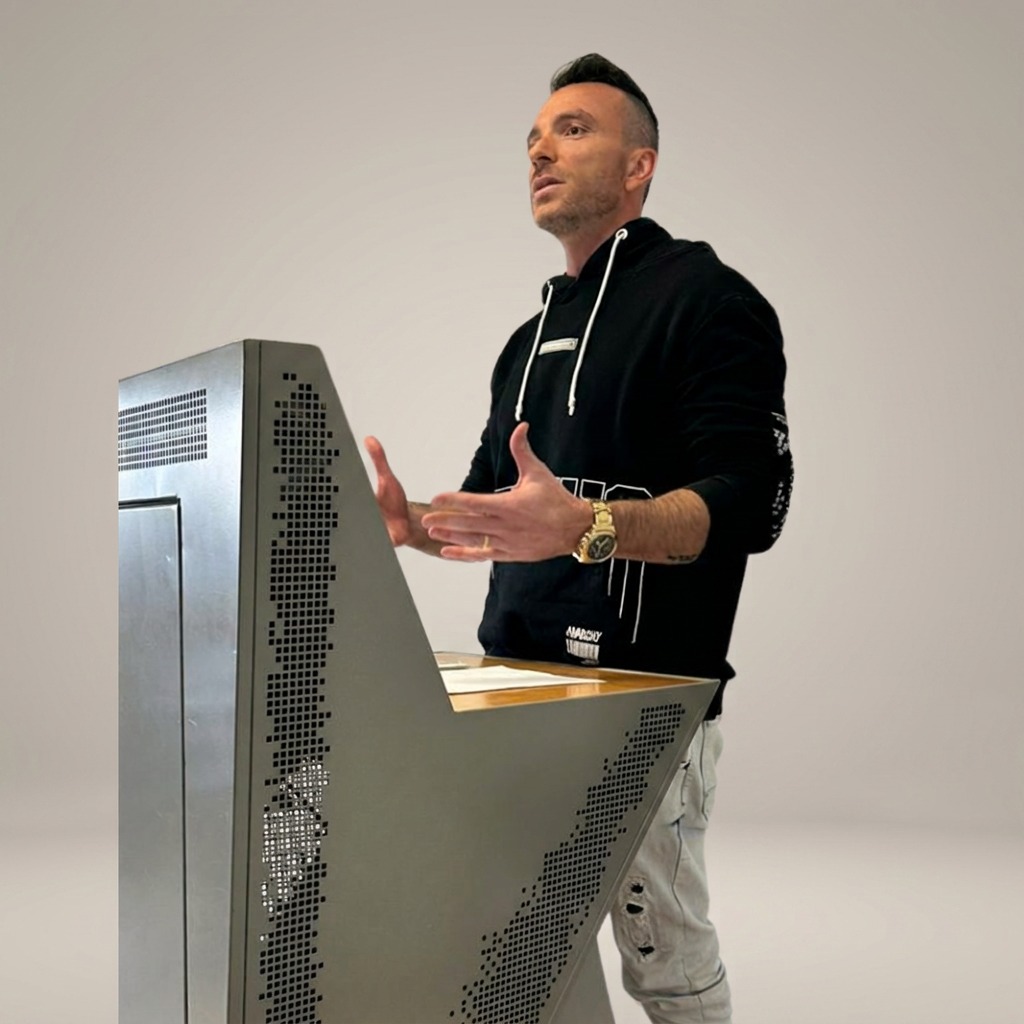 סיימון ניגל מרצה מאחורי דוכן ההרצאות